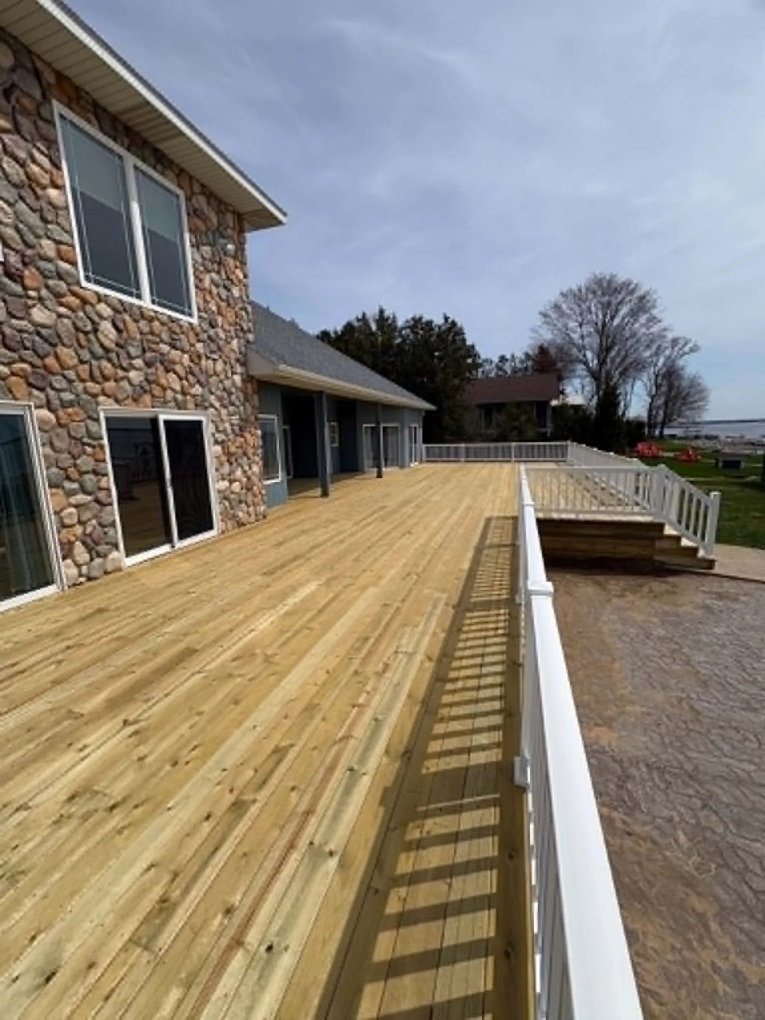Long new wood deck running beside a stone-sided home