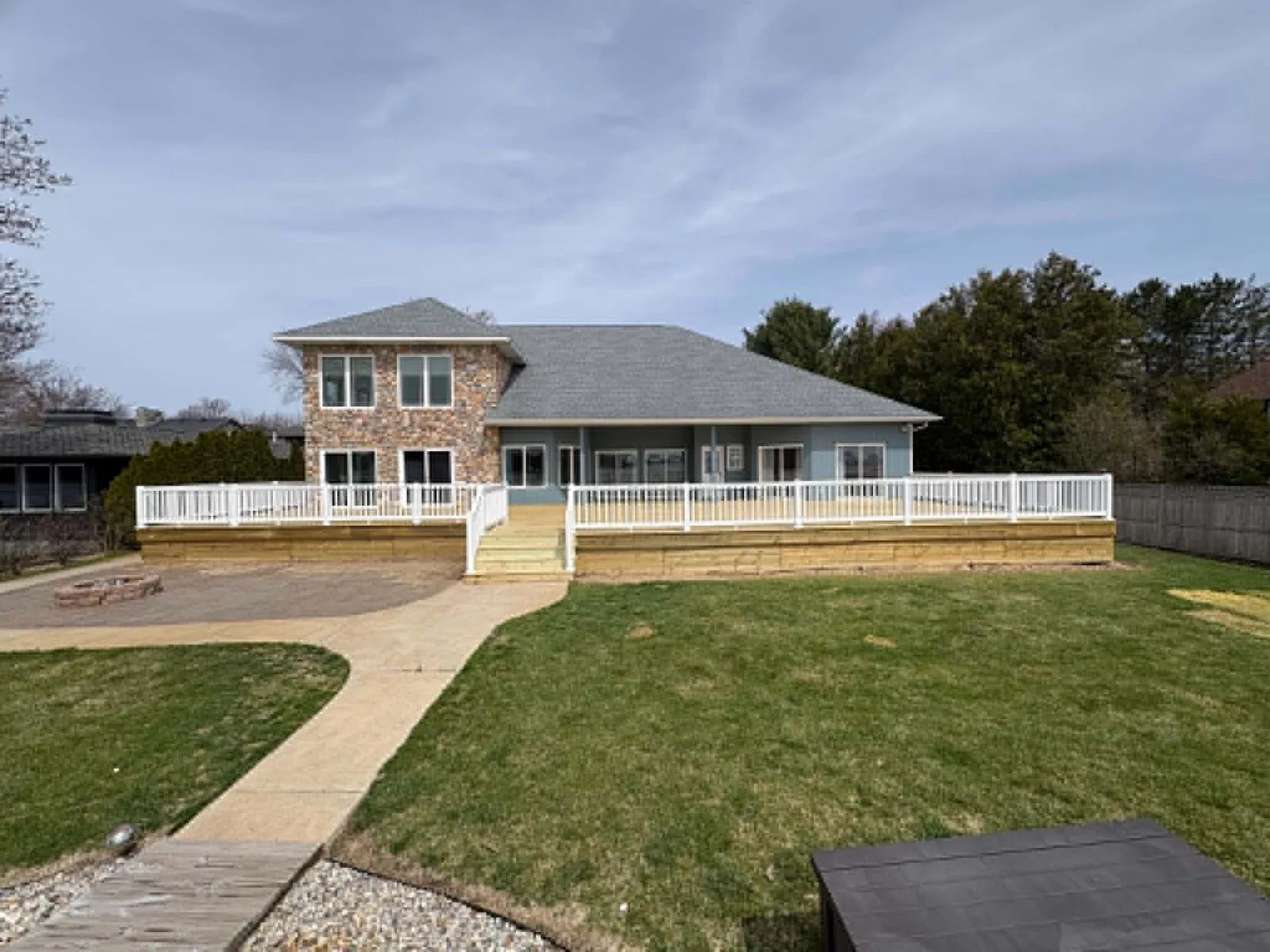 Full rear view of a home with a large finished deck and white railings