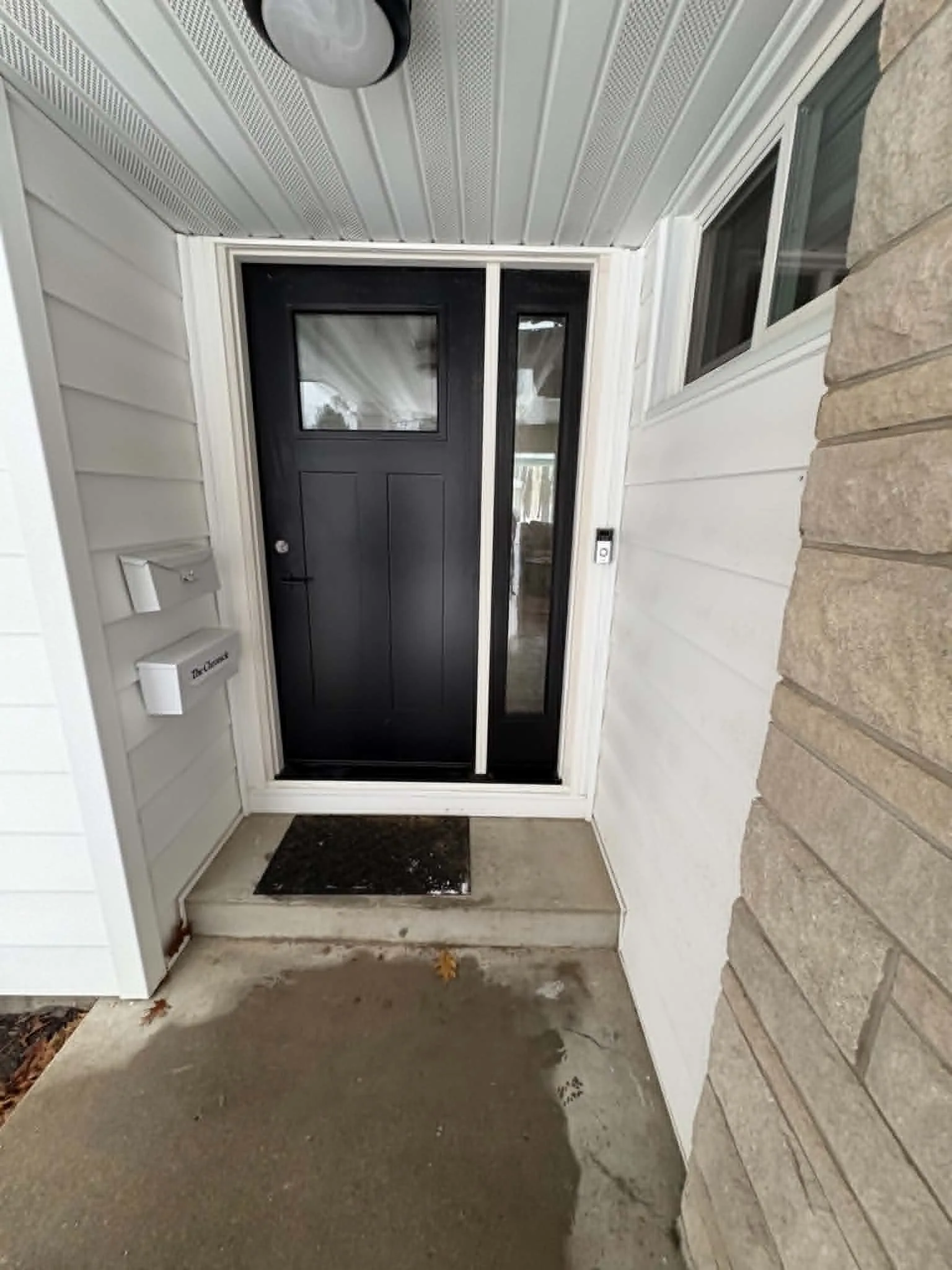 New black exterior entry door with white trim and updated threshold