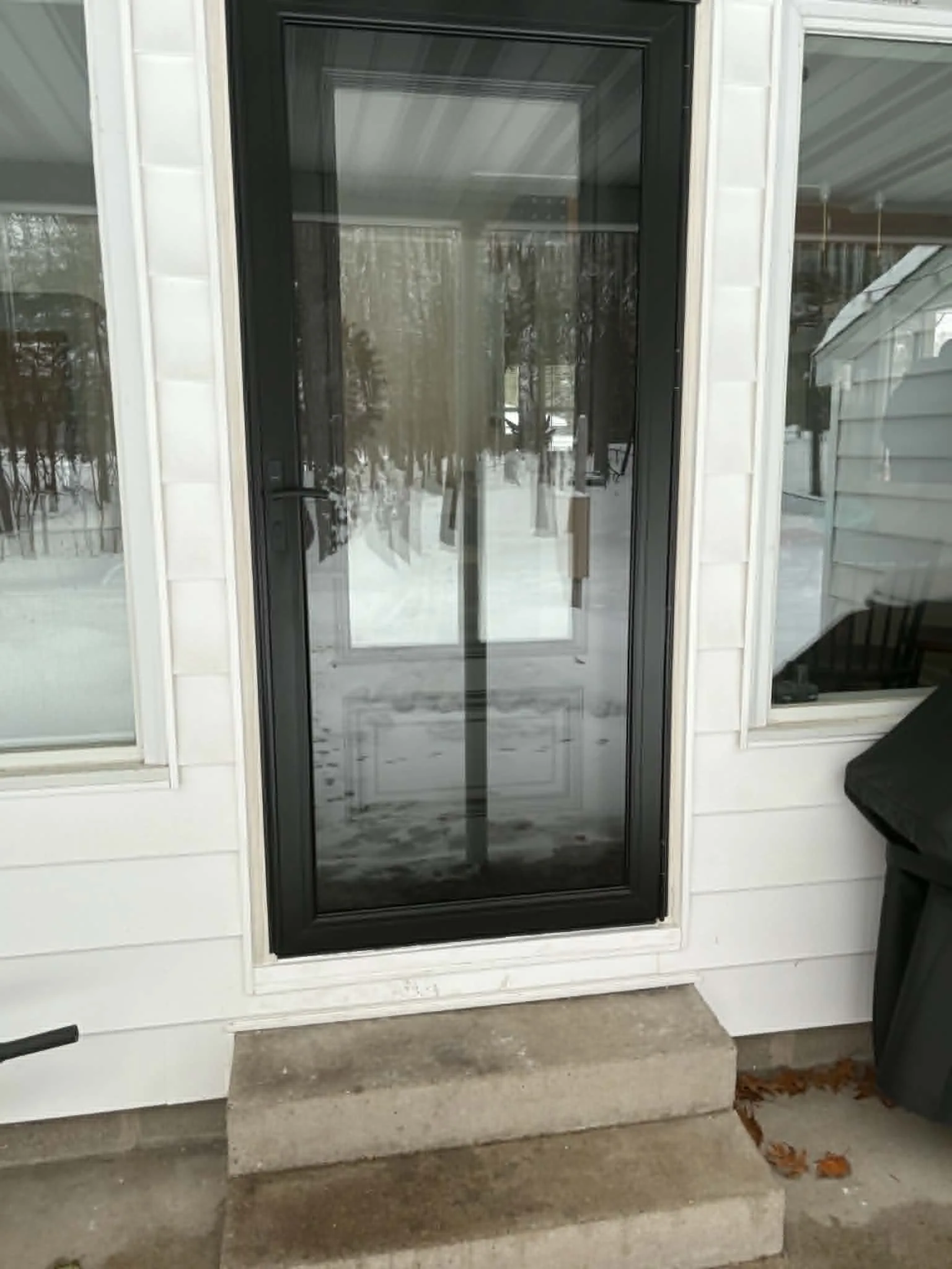Black full-view storm door installed between two exterior windows