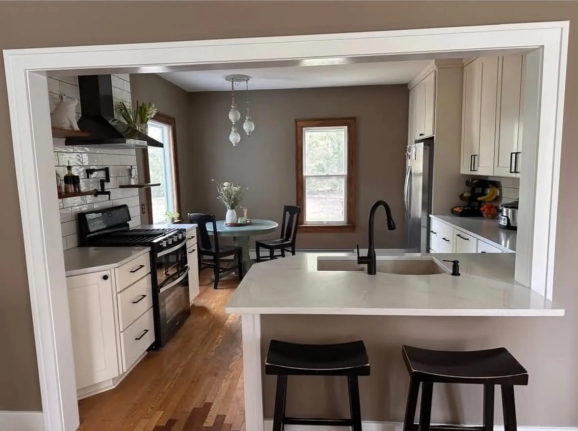 Finished kitchen renovation with white cabinets, center island, and pendant lighting