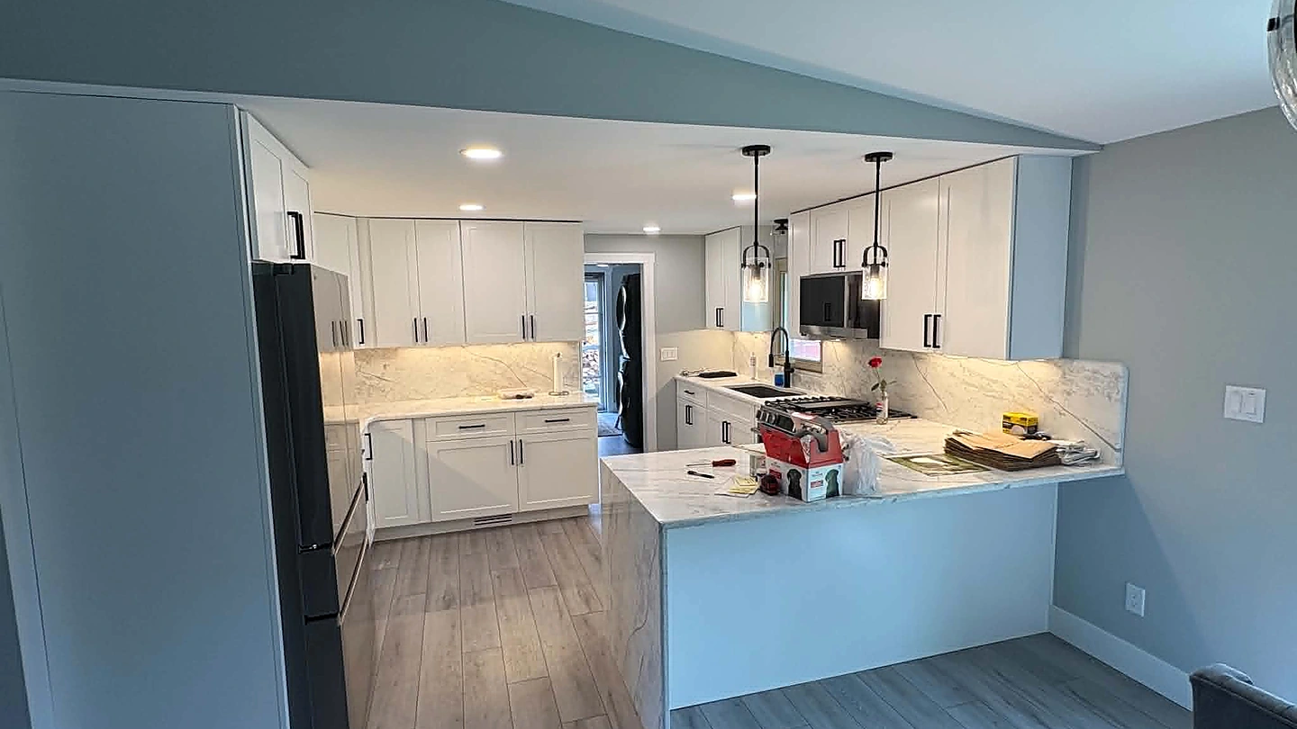 Finished open kitchen with white cabinetry, peninsula seating, and new flooring
