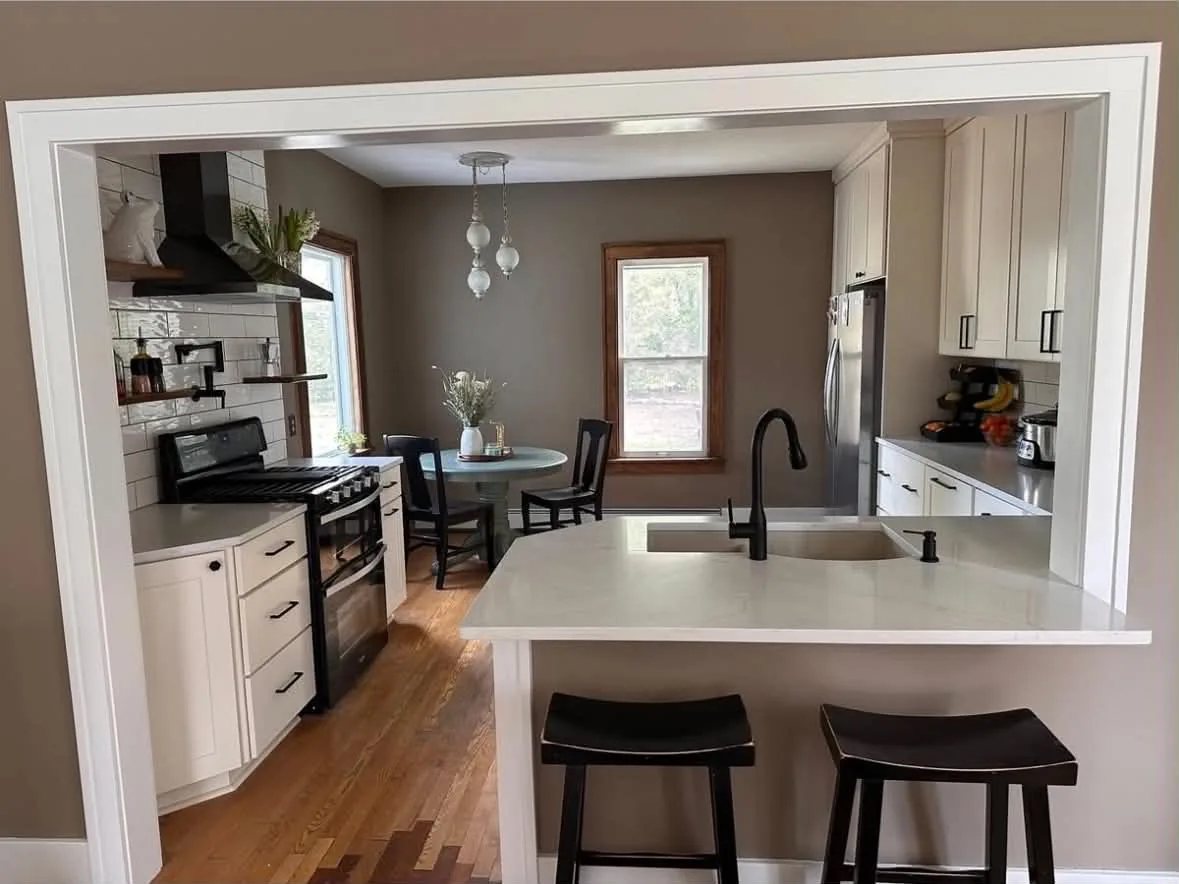 Renovated kitchen opened to the dining area with white cabinets and wood floors