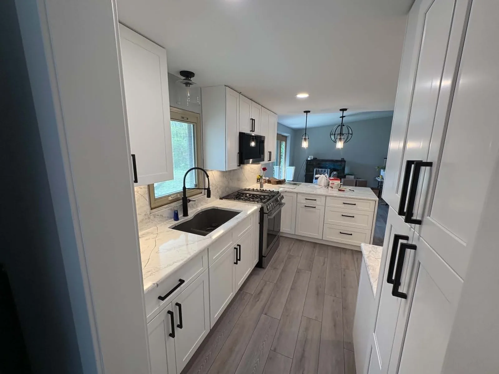 Finished galley kitchen with white cabinetry, black fixtures, and stone-look counters