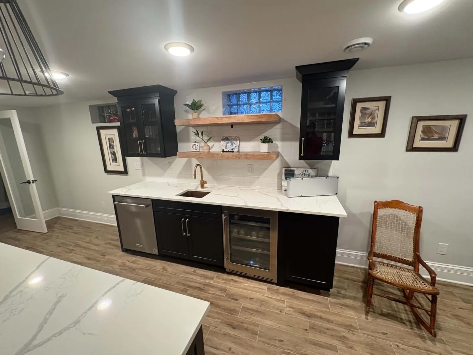 Finished custom beverage station with black cabinetry, floating wood shelves, and a quartz counter